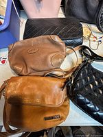 Top view of six purses showing variety of materials and colors including brown leather and black quilted styles