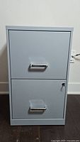 Front view of gray metal 2-drawer filing cabinet with lock on bottom drawer and key inserted
