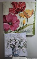 Two floral canvas paintings shown together, larger with red, pink, orange flowers, smaller with white flowers in a vase.