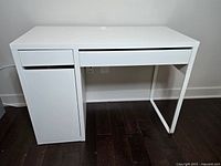 Front and full view of the white IKEA Micke desk showing the desktop, drawer, cabinet, and metal leg frame.