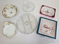 Full view of the lot showing two vintage Limoges bowls, two clear glass divided serving platters, and two boxed Juliska Christmas square platters
