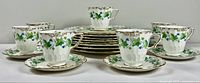 Set of 7 teacups with matching saucers placed in front of stacked luncheon plates showing design and quantity