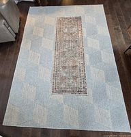 Top-down view of area rug with geometric pattern and small runner rug centered on top.