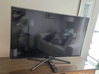 Samsung 40-inch LED television turned off on a wooden surface with remote control placed in front.