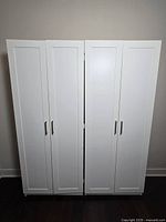 Front view of two white storage cabinets side by side showing doors and handles