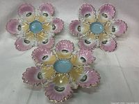 Three pink and yellow gradient porcelain oyster plates arranged showing radial wells and blue centers