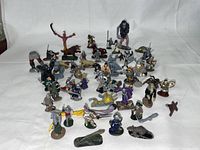 Wide view of entire miniature collection arranged on a white cloth background showing fantasy and medieval metal miniatures including warriors, mythical creatures, and armored knights.