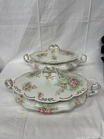 Front view of two tureens with lids showing floral and gold designs.