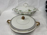 Two antique tureens displayed together, showing size difference and details