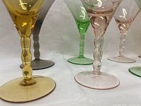 Close-up showing detail of the twisted stems and the variety of jewel tone colors including amber yellow, smoky gray, green, and pink.