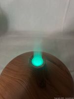 Ultrasonic diffuser emitting mist with green ambient light