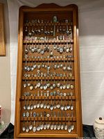 Full view of wooden display case filled with 89 miniature collectible spoons arranged in rows.
