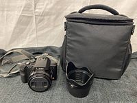 Panasonic Lumix DMC-FZ28 camera, lens hood, and camera carrying case displayed on black textured surface.