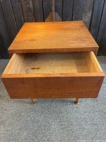 Front view of the nightstand with the drawer open, showing wood grain and interior staining of drawer.
