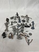 Wide view showing entire collection of metal miniatures and accessories arranged on white cloth background.