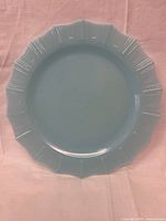Top view of a single vintage Pyrex Delphite Blue plate showing its scalloped edge design and even color tone.