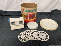 View of all included items: the View-Master viewer, seven slide reels, and original container with lid.