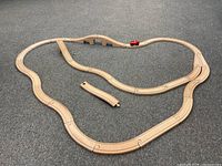 Full layout of wooden train set with interlocking track pieces forming a loop with a bridge and a small red train engine on the tracks.