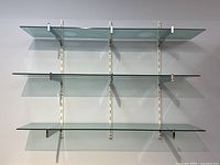Front view of the 3-tier glass wall shelf showing all shelves and supports.
