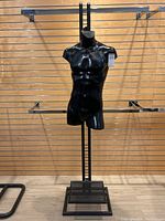 Full view of black male torso mannequin on metal stand against wood slatwall