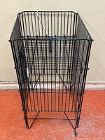 Full front view of a tall black metal wire basket with square shape and open wire grid construction