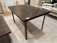 Angled side view of oak veneer table with steel legs, showing the wood grain on the tabletop and condition of leg base.