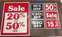 Large red sale sign 20% to 50% Off along with various smaller black and red discount signs.