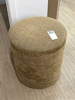 Round foot stool ottoman showing side profile and fabric texture on cylindrical shape.