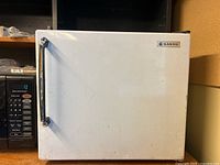 Front view of the vintage Sanyo mini fridge showing white exterior, black handle, and Sanyo logo.