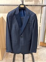 Full front view of navy blue tuxedo jacket on hanger