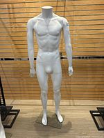 Front full view of the white male mannequin standing on a clear glass base with no head.