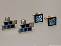 Both pairs of cufflinks side by side on a plain background showing their shapes and inlay designs