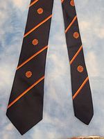 Full view of the vintage CBC necktie displaying its pattern and colors against a blue background.