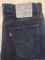 Back view of dark blue Levi's 551 Z jeans showing the unique worn leather patch and red Levi's tab on back pocket.