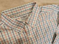 Close-up of collar and label showing LL Bean Traditional Fit tag and button details on checked cotton fabric