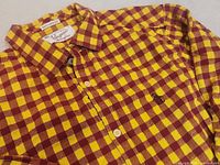 Close-up of the yellow and red checkered slim fit shirt showing collar, front buttons, and embroidered Penguin logo on chest pocket.