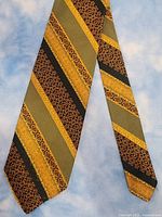 Front side of necktie showing wide diagonal stripes in olive green, gold, black, and patterned designs.