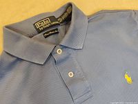 Close up photo showing the Polo by Ralph Lauren tag and collar area of the shirt, verifying brand and fabric line.