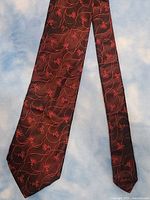 Front view of brown necktie with abstract red floral/vine pattern
