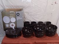 16 piece dark brown dinnerware set with plates, bowls, and mugs, arranged in front of original box.