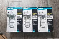 Three boxed Woods brand industrial style indoor/outdoor wall lights with steel protective cages and labeled vandal resistant.