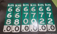 Front view of six retired green and white highway marker road signs showing km markings 668.0, 670.0, 672.0.