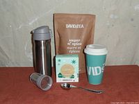 Photo showing the stainless steel travel mug, ceramic mug with lid, metal tea scoop, tea filters, and Sugar n' Spice loose leaf tea package.