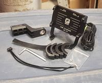 Full view of all components included in the lot: phone holder, mounting bracket, clamp rubber spacers, screws, Allen wrench, and zip ties, arranged on a grey surface.