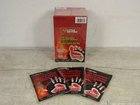 Photo of three Little Hotties hand warmer packets displayed in front of a large box of Little Hotties toe warmers.