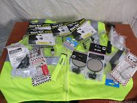 Display of all items laid out on a high visibility vest including packaged mirrors, a pump, and various cycling safety accessories.