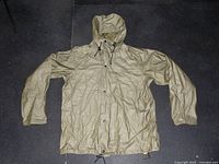 Front view of olive drab military rain jacket showing hood, long sleeves, and front snap button closure.