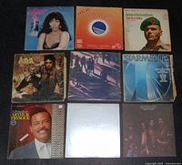 Top view of 9 vinyl records arranged in 3 rows, showing front covers including Donna Summer, Now Disco, Eagles, Steve Stevens, Starmania, Arthur Prysock, and others.