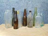 Front view of nine vintage liquor glass bottles showing various shapes, colors, and embossing