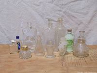 Wide shot of all 10 vintage glass perfume and cologne bottles on neutral background
